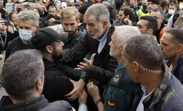 Spain's King Felipe VI, centre, speaks with protesters in Paiporta, near Valencia, Spain, Sunday Nov. 3, 2024. A crowd of angry survivors of Spain's floods have tossed mud and shouted insults at Spain's King Felipe VI and government officials when they made their first visit to one of the hardest hit towns. (Biel Alino/EFE via AP)