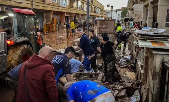 People clean their houses affected by floods in Utiel, Spain, Wednesday, Oct. 30, 2024. (AP Photo/Manu Fernandez)