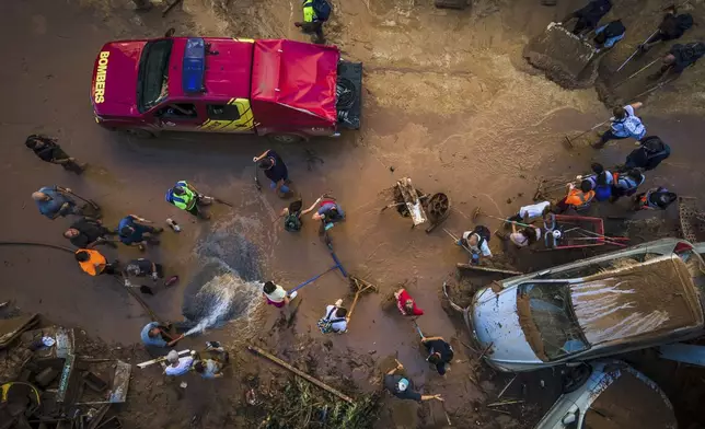 Volunteers and residents clean the mud four days after flash floods swept away everything in their path in Paiporta, outskirts of Valencia, Spain, Saturday, Nov. 2, 2024.(AP Photo/Angel Garcia)