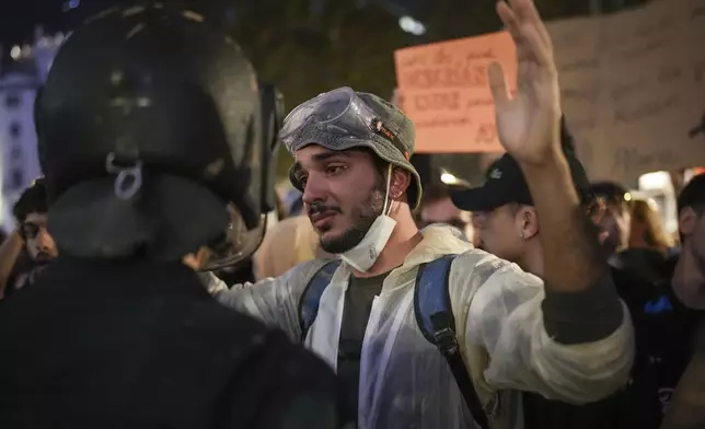 A demonstrator holds his hands up in front of riot police during a protest organized by social and civic groups, denouncing the handling of recent flooding under the slogan "Mazón, Resign," aimed at the president of the regional government Carlos Mazon, in Valencia, Spain, Saturday, Nov. 9, 2024. (AP Photo/Emilio Morenatti)