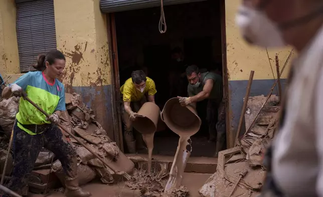 People clean mud from a house affected by floods, in Algemesi, Spain, Sunday, Nov. 3, 2024. (AP Photo/Manu Fernandez)