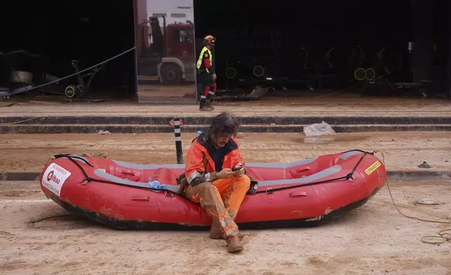 A firefighter sits on a dingy waiting to enter a flooded underground car park in the MN4 shopping centre as the search for bodies continues on the outskirts of Valencia, Spain, Monday, Nov. 4, 2024. (AP Photo/Alberto Saiz)