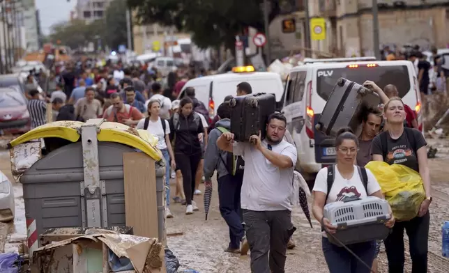 Residents carry their belongings as they leave their houses affected by floods in Valencia, Spain, Thursday, Oct. 31, 2024. (AP Photo/Alberto Saiz)