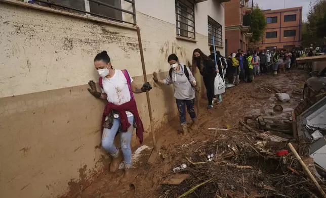 Volunteers walk in the mud to help with the clean up operation after floods in Massanassa, just outside of Valencia, Spain, Saturday, Nov. 2, 2024. (AP Photo/Alberto Saiz)