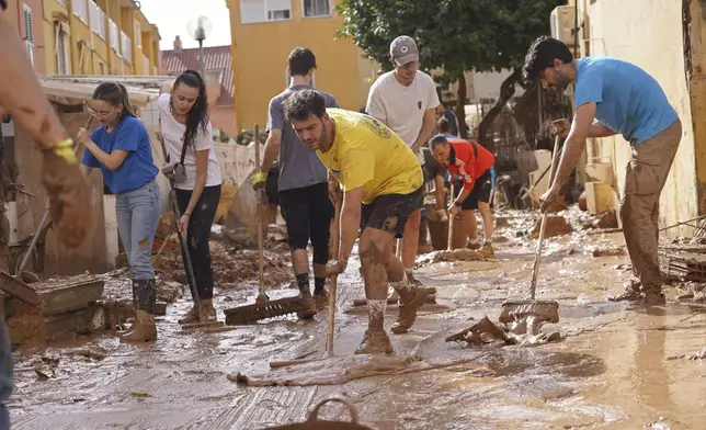 People clear mud from the street after floods in Massanassa, just outside of Valencia, Spain, Friday, Nov. 1, 2024. (AP Photo/Alberto Saiz)