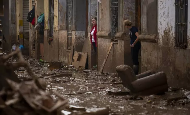 Women stand at the entrance of their houses affected by flooding in Masanasa, Valencia, Spain, Wednesday, Nov. 6, 2024. (AP Photo/Emilio Morenatti)