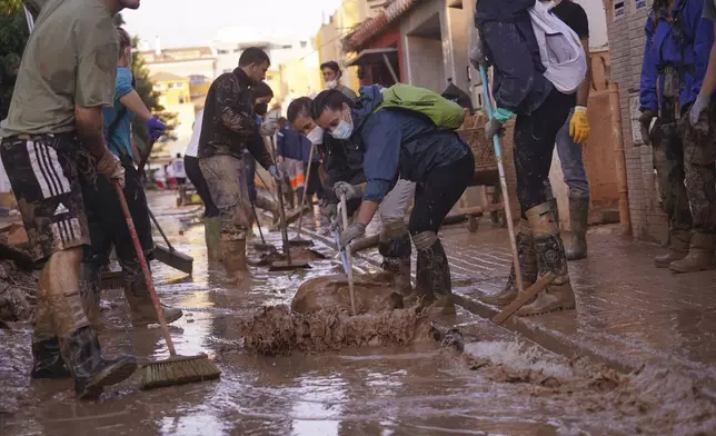 People sweep away mud during the clean up operation after flooding in Massanassa on the outskirts of Valencia, Spain, Wednesday, Nov. 6, 2024. (AP Photo/Alberto Saiz)