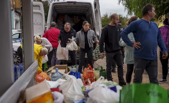 People collect food in an area affected by floods in Chiva, Spain, Friday, Nov. 1, 2024. (AP Photo/Manu Fernandez)