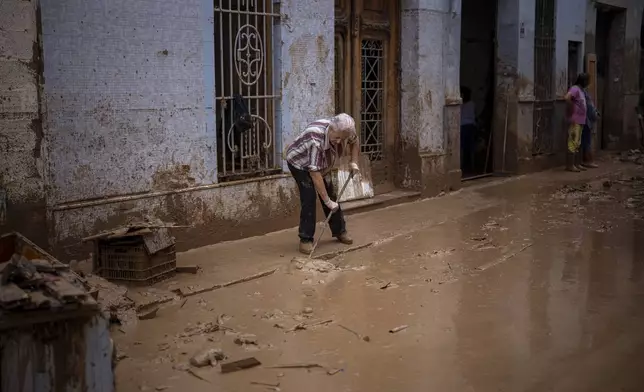 Maria Munoz, 74, cleans the mud outside her house, where she was born and which was badly affected by flooding in Masanasa, Valencia, Spain, Wednesday, Nov. 6, 2024. (AP Photo/Emilio Morenatti)