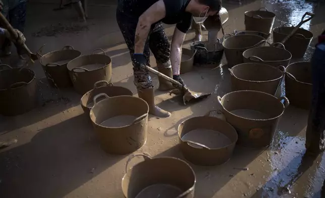 Volunteers clean up the mud accumulated by the floods in Masanasa, Valencia, Spain, Thursday, Nov. 7, 2024. (AP Photo/Emilio Morenatti)