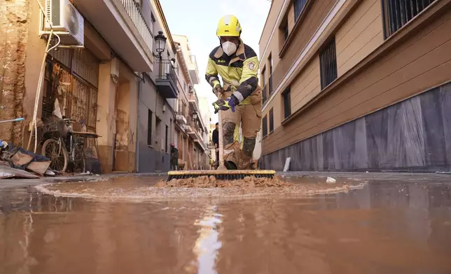 A firefighter sweeps away mud after floods in Paiporta, Spain, Thursday, Nov. 7, 2024. (AP Photo/Alberto Saiz)