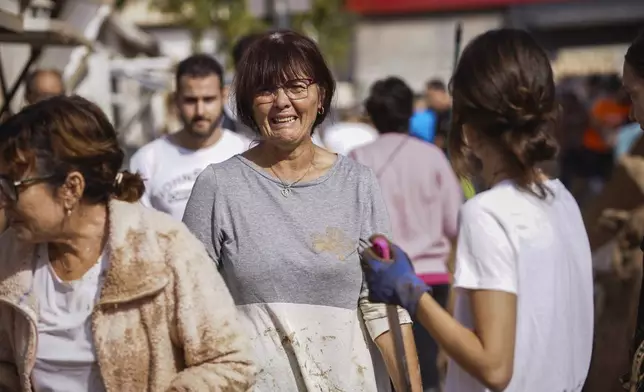 A woman reacts as residents clean up an area affected by floods in Valencia, Spain, Friday, Nov. 1, 2024. (AP Photo/Alberto Saiz)