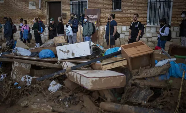 Residents wait for public transportation in an area, affected by floods, in Paiporta, Valencia, Spain, Tuesday, Nov. 5, 2024. (AP Photo/Emilio Morenatti)