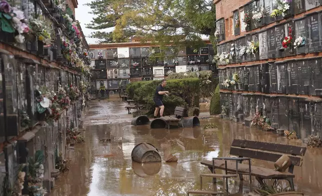 A man walks inside a flood damaged cemetery on the outskirts of Valencia, Spain, Friday, Nov. 1, 2024 after flooding in the region. (AP Photo/Alberto Saiz)