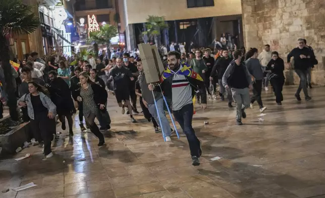 Demonstrators run away from riot police during minor clashes after a peaceful protest organized by social and civic groups, denouncing the handling of recent flooding under the slogan "Mazon, Resign," aimed at the president of the regional government Carlos Mazon, in Valencia, Spain, Saturday, Nov. 9, 2024. (AP Photo/Emilio Morenatti)