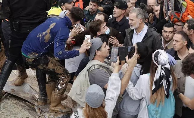 Spain's King Felipe VI, centre right, speaks with protesters in Paiporta, near Valencia, Spain, A crowd of angry survivors of Spain's floods have tossed mud and shouted insults at Spain's King Felipe VI and government officials when they made their first visit to one of the hardest hit towns. (Biel Alino/EFE via AP)