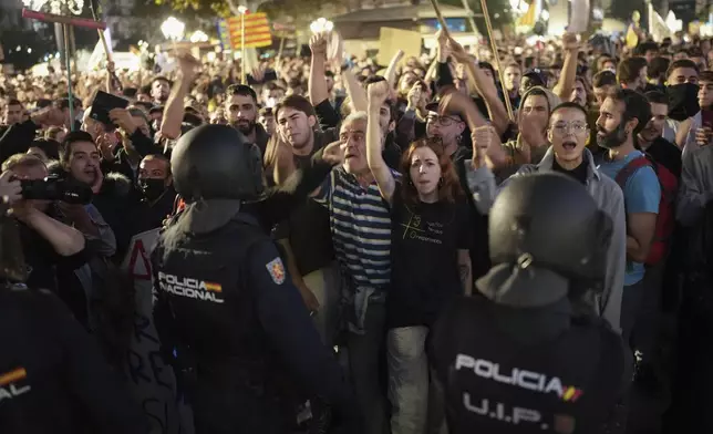 Demonstrators confront riot police during a protest organized by social and civic groups, denouncing the handling of recent flooding under the slogan "Mazón, Resign," aimed at the president of the regional government Carlos Mazon, in Valencia, Spain, Saturday, Nov. 9, 2024. (AP Photo/Emilio Morenatti)