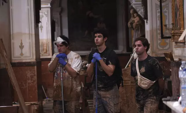 People who have been working in the clean-up attend a mass at the San Jorge church after floods in Paiporta, Spain, Thursday, Nov. 7, 2024. (AP Photo/Alberto Saiz)