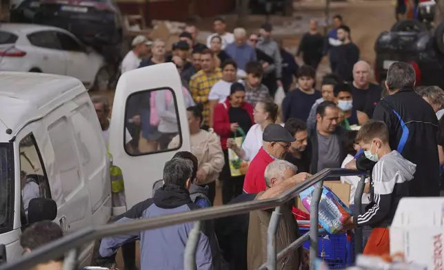 Food and water are given out to residents after floods in Massanassa, just outside of Valencia, Spain, Saturday, Nov. 2, 2024. (AP Photo/Alberto Saiz)