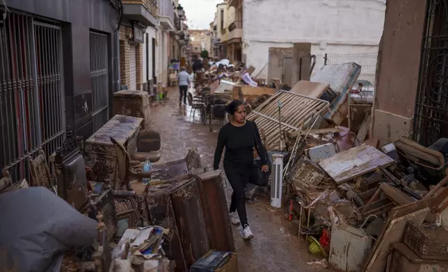 A woman walks through the street in an area affected by floods in Sedavi, Spain, Friday, Nov. 1, 2024. (AP Photo/Manu Fernandez)