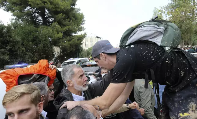 Spain's King Felipe VI listens to a person affected by the floods after a crowd of angry survivors of Spain's floods tossed mud and shouted insults at the King and government officials when they made their first visit to one of the hardest hit towns after floods in Paiporta near Valencia, Spain, Sunday, Nov. 3, 2024. (AP Photo/Hugo Torres)