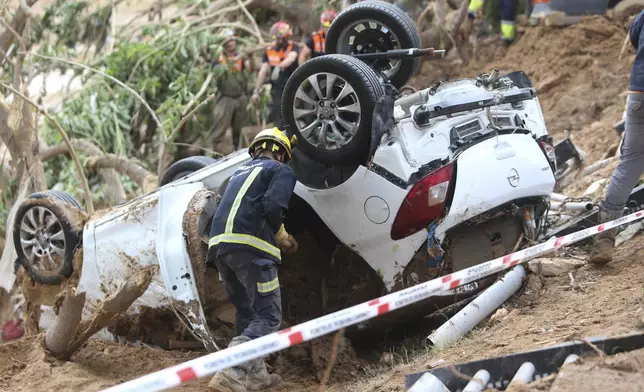 A rescue worker checks a car after floods in Paiporta near Valencia, Spain, Sunday, Nov. 3, 2024. (AP Photo/Hugo Torres)