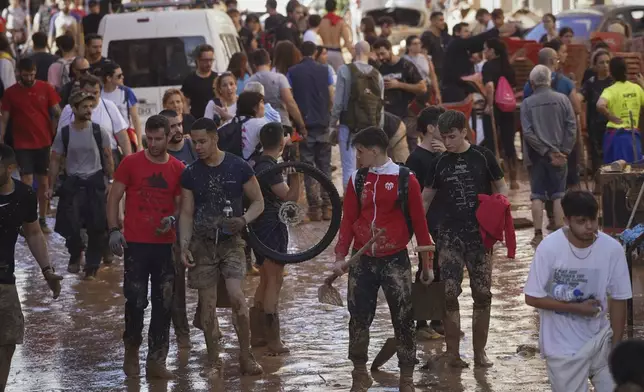 People walks through the mud at an area affected by floods in Paiporta, near Valencia, Spain, Friday, Nov. 1, 2024. (AP Photo/Alberto Saiz)