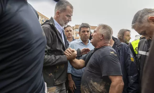 Spain's King Felipe VI speaks with people amidst angry Spanish flood survivors in Paiporta, near Valencia, Spain, Sunday Nov. 3, 2024. (AP Photo/David Melero)