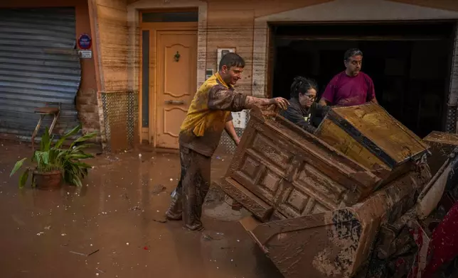 People clean their houses affected by floods in Utiel, Spain, Wednesday, Oct. 30, 2024. (AP Photo/Manu Fernandez)