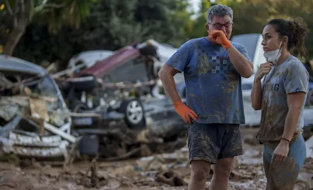 A man reacts in an area affected by floods, with cars piled up in the background in Benetusser, Spain, Saturday, Nov. 2, 2024. (AP Photo/Manu Fernandez)