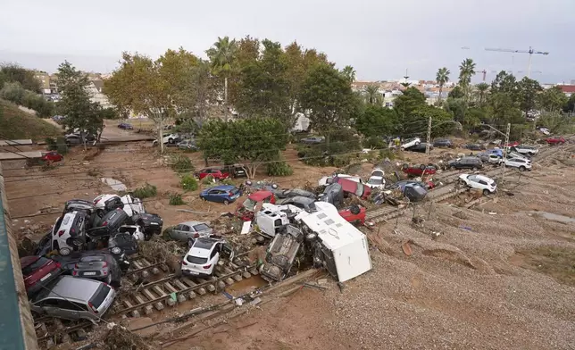 Vehicles are strewn across railway tracks after floods on the outskirts of Valencia, Spain, Friday, Nov. 1, 2024. (AP Photo/Alberto Saiz)