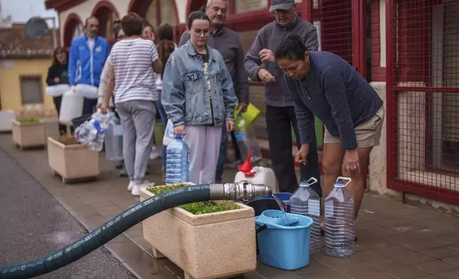 People collect water in an area affected by flooding in Chiva, Spain, Friday, Nov. 1, 2024. (AP Photo/Manu Fernandez)