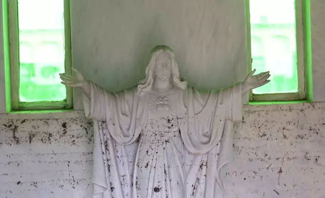 A mud splattered statue of Christ is seen inside a cemetery on the outskirts of Valencia, Spain, Friday, Nov. 1, 2024 after flooding in the region. (AP Photo/Alberto Saiz)