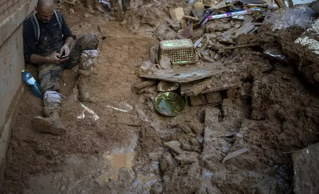 A volunteer takes a break near to the house where he clears up the mud accumulated by the floods, in Masanasa, Valencia, Spain, Thursday, Nov. 7, 2024. (AP Photo/Emilio Morenatti)