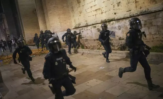 Riot police chases demonstrators during minor clashes after a peaceful protest organized by social and civic groups, denouncing the handling of recent flooding under the slogan "Mazón, Resign," aimed at the president of the regional government Carlos Mazon, in Valencia, Spain, Saturday, Nov. 9, 2024. (AP Photo/Emilio Morenatti)