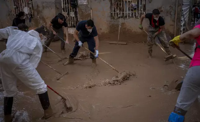 Members of the army, police and volunteers clean the mud after the floods, in Masanasa, Valencia, Spain, Thursday, Nov. 7, 2024. (AP Photo/Emilio Morenatti)