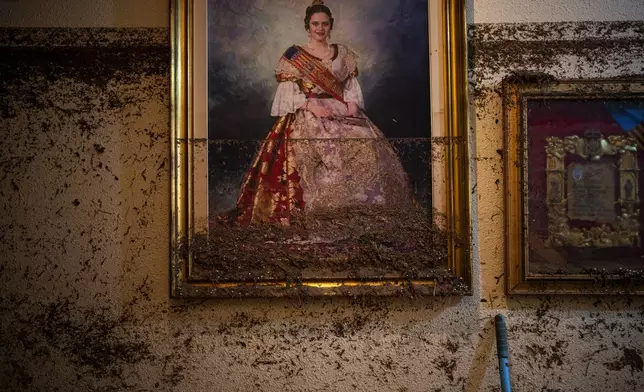 A painting hangs near the water level marker in an area affected by floods in Paiporta, Valencia, Spain, Tuesday, Nov. 5, 2024. (AP Photo/Emilio Morenatti)