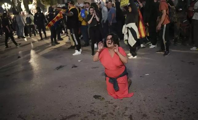 A demonstrator kneels in front of riot police during a protest organized by social and civic groups, denouncing the handling of recent flooding under the slogan "Mazón, Resign," aimed at the president of the regional government Carlos Mazon, in Valencia, Spain, Saturday, Nov. 9, 2024. (AP Photo/Emilio Morenatti)