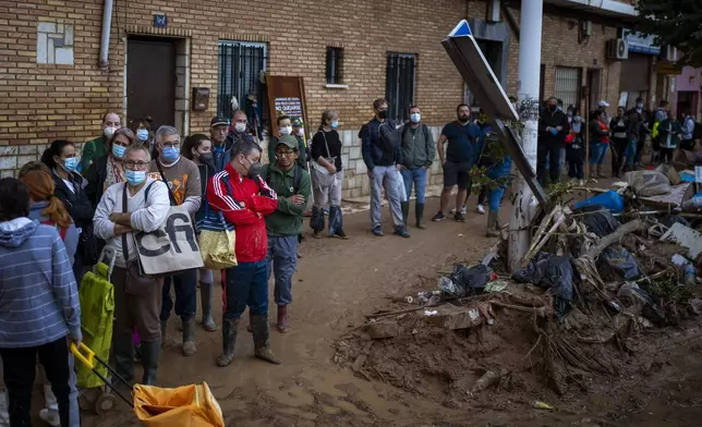 Residents wait for public transportation in an area, affected by floods, in Paiporta, Valencia, Spain, Tuesday, Nov. 5, 2024. (AP Photo/Emilio Morenatti)