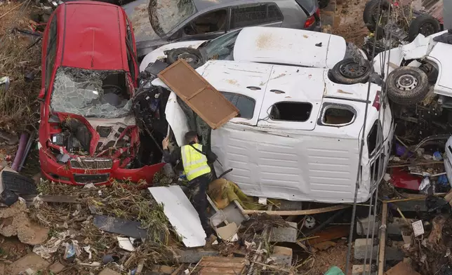 A civil guard searches for survivors in vehicles piled up on the outskirts of Valencia, Spain, Friday, Nov. 1, 2024 after flooding. (AP Photo/Alberto Saiz)