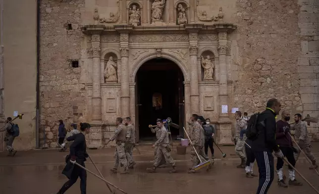 Spanish soldiers walk in front of the Basilica of Saint James the Apostle in an area affected by floods, in Algemesi, Spain, Sunday, Nov. 3, 2024. (AP Photo/Manu Fernandez)