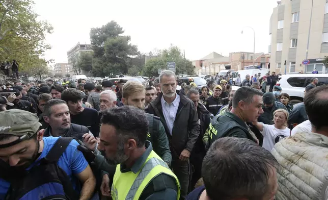 Spain's King Felipe VI, centre, leaves the scene after crowd of angry survivors of Spain's floods have tossed mud and shouted insults at the King and government officials when they made their first visit to one of the hardest hit towns. after floods in Paiporta near Valencia, Spain, Sunday, Nov. 3, 2024. (AP Photo/Hugo Torres)