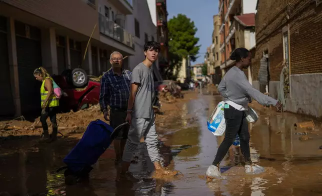 People walk in an area affected by floods in Valencia, Spain, Thursday, Oct. 31, 2024. (AP Photo/Manu Fernandez)