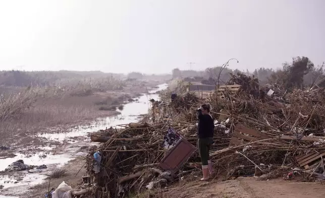 A woman looks out next to flood debris in Barranco de Chiva on the outskirts of Valencia, Spain, Wednesday, Nov. 6, 2024. (AP Photo/Alberto Saiz)