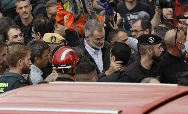 Spain's King Felipe VI, centre, speaks with protesters in Paiporta, near valencia, Spain, A crowd of angry survivors of Spain's floods have tossed mud and shouted insults at Spain's King Felipe VI and government officials when they made their first visit to one of the hardest hit towns. (Biel Alino/EFE via AP)