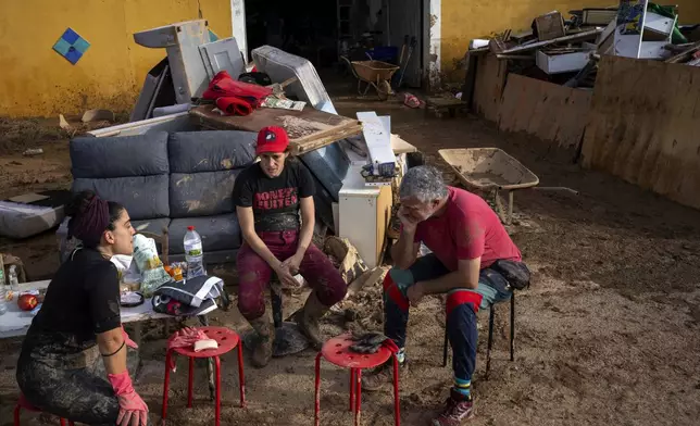 Members of a theatre company sit with their muddy belongings after the floods in the outskirts of Valencia, Spain, Friday, Nov. 8, 2024. (AP Photo/Emilio Morenatti)