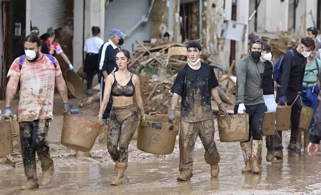 Volunteers carry buckets of mud after floods in Paiporta, Spain, Sunday, Nov. 3, 2024. (AP Photo/Hugo Torres)