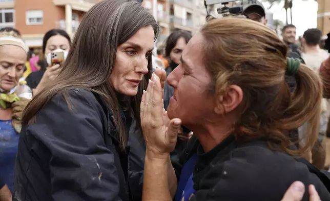 Spain's Queen Letizia, left, conforts a woman affected by the floods in Paiporta, near Valencia, Spain, Sunday Nov. 3, 2024. A crowd of angry survivors of Spain's floods have tossed mud and shouted insults at Spain's King Felipe VI and government officials when they made their first visit to one of the hardest hit towns. (Ana Escobar/EFE via AP)