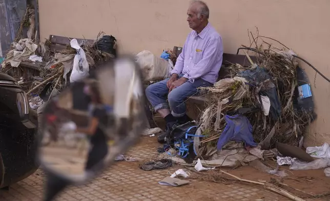 A man sits among debris after floods in Paiporta, Spain, Thursday, Nov. 7, 2024. (AP Photo/Alberto Saiz)