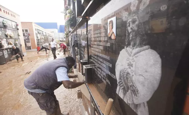 Workers repair damaged tombstones and clean mud inside a cemetery on the outskirts of Valencia, Spain, Friday, Nov. 1, 2024 after flooding in the region. (AP Photo/Alberto Saiz)